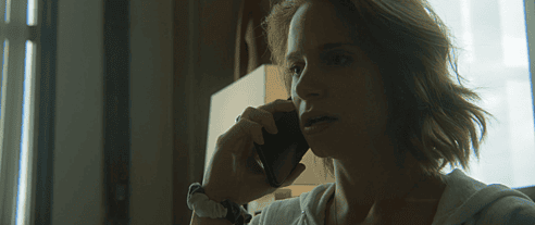 A pensive woman looks shocked as she receives disturbing news from a phone call in a production still from the short film "Telehealth" produced in part by Tame Rabbit.